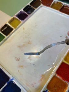Bent palette knife fits into paint wells